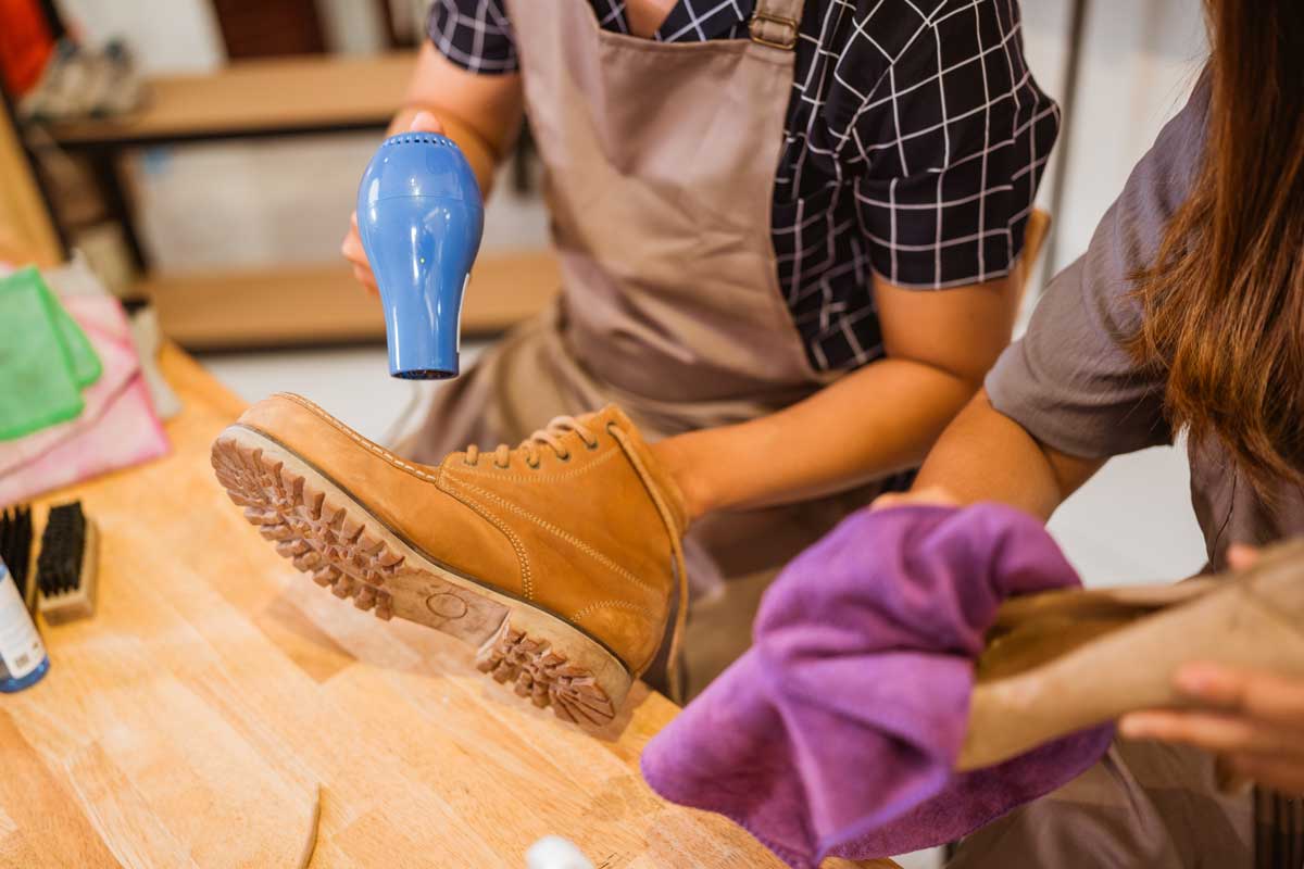 Sušení kožené zimní boty fénem na pracovním stole