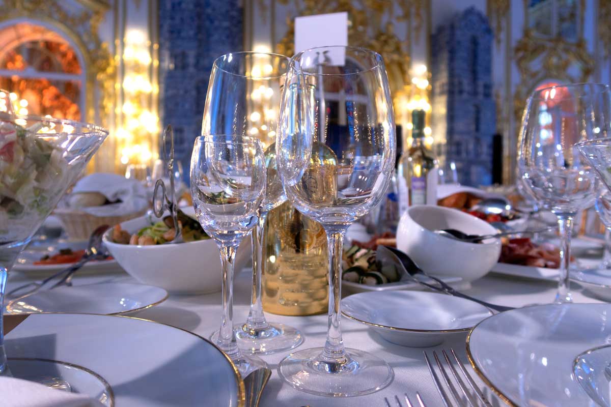 Detail slavnostně prostřeného stolu s čistými, lesklými sklenicemi připravenými k servírování.