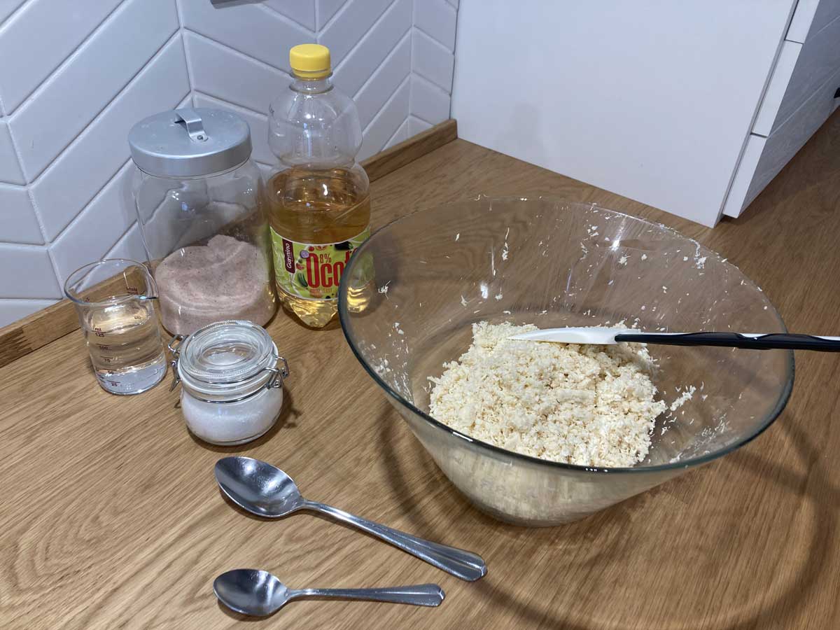 Dochucování nastrouhaného křenu olejem, octem, solí a vodou při přípravě křenu ke grilovanému masu.