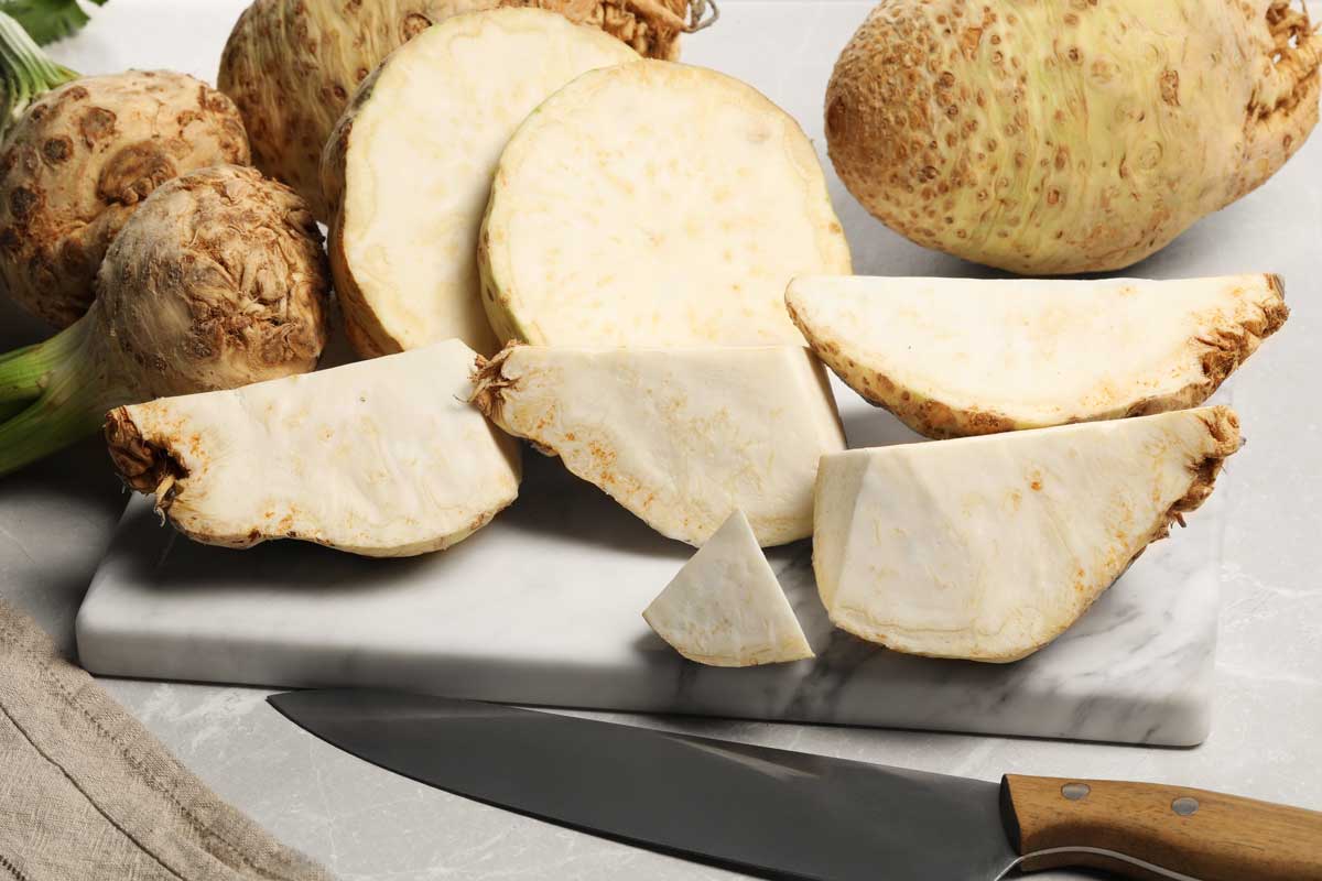 celer Nakrájený bulvový celer na prkénku s kuchyňským nožem