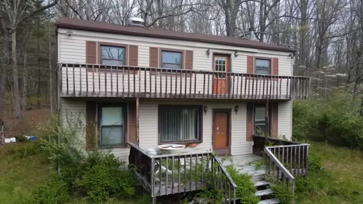 Opuštěný dům před rekonstrukcí obklopený zelení s původní fasádou a terasou