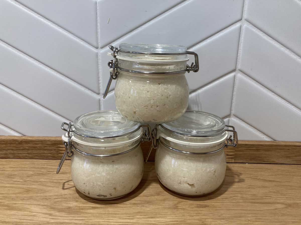 Domácí nakládaný křen uložený ve sklenicích připravený k dlouhodobému uchování.