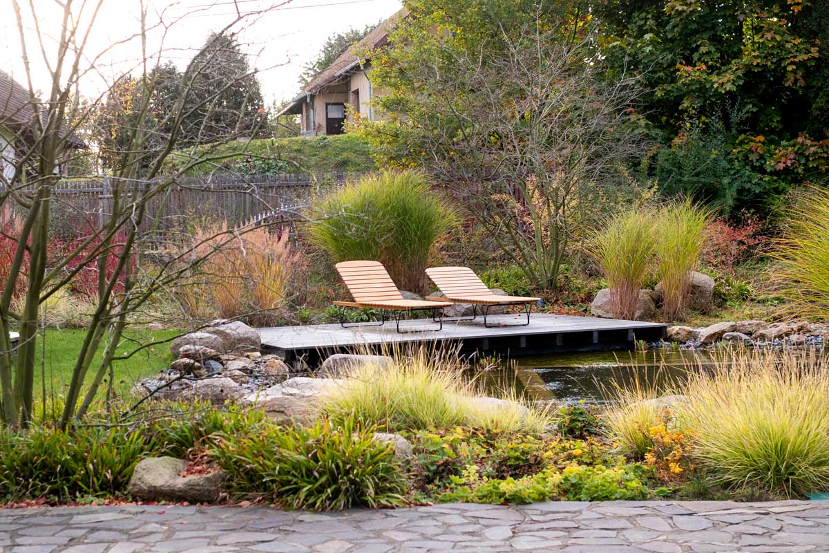 oddechova cast lehatka Odpočinková část u jezírka s dřevěným molem a lehátky zasazenými do zeleně.