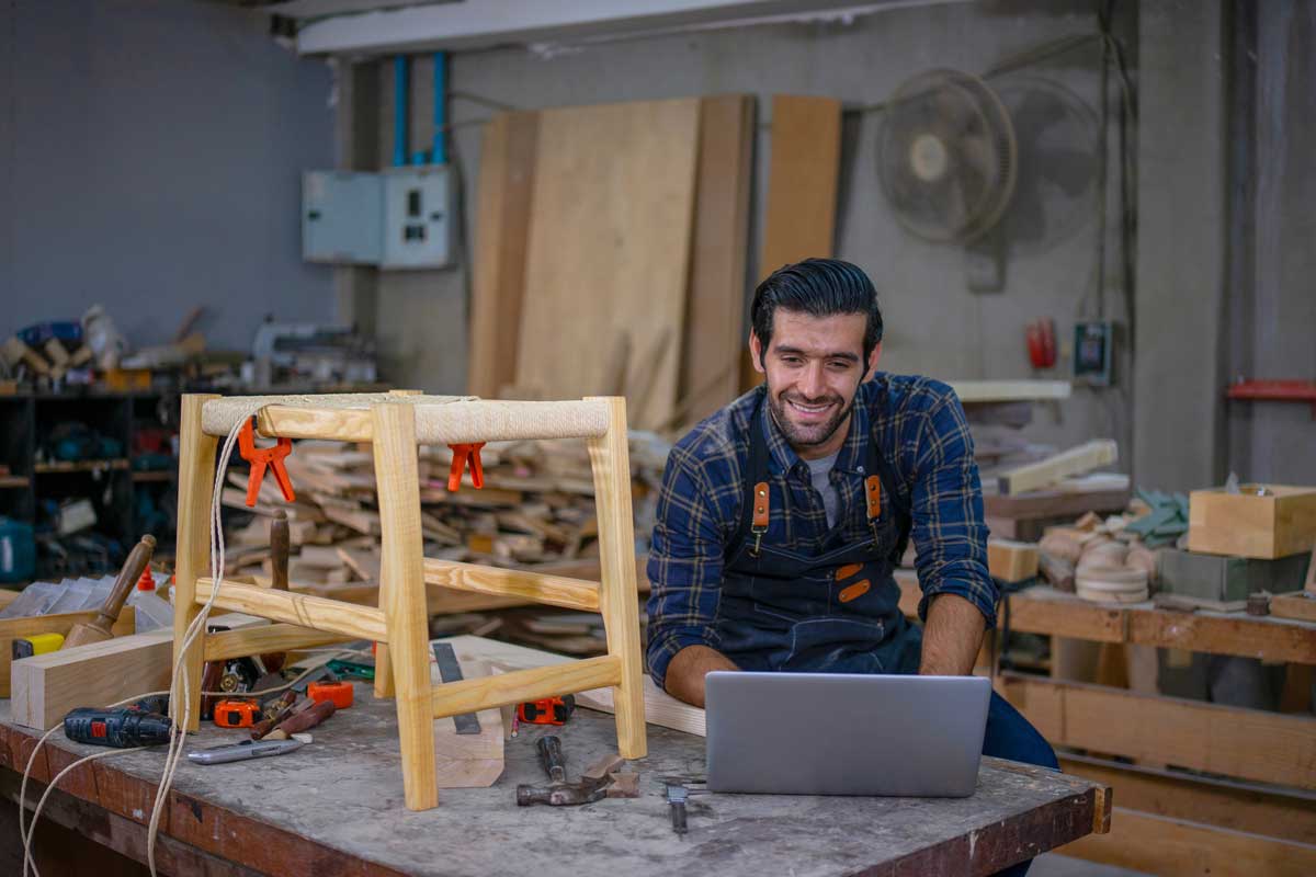 Truhlář sledující videonávod při výrobě dřevěného nábytku
