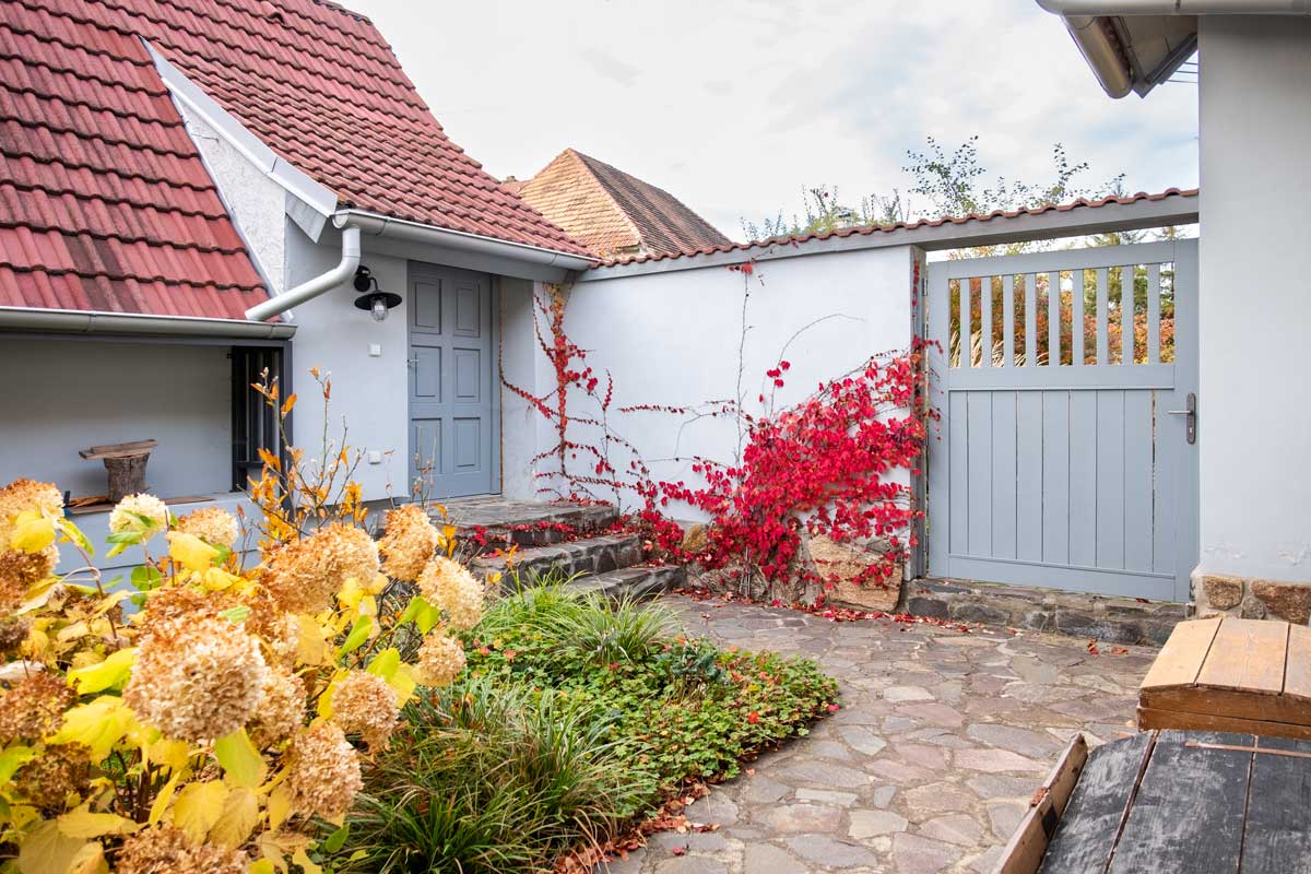 vstup a brana Vstupní dvorek s kamennou dlažbou, popínavými rostlinami a bránou oddělující zahradu od okolí.