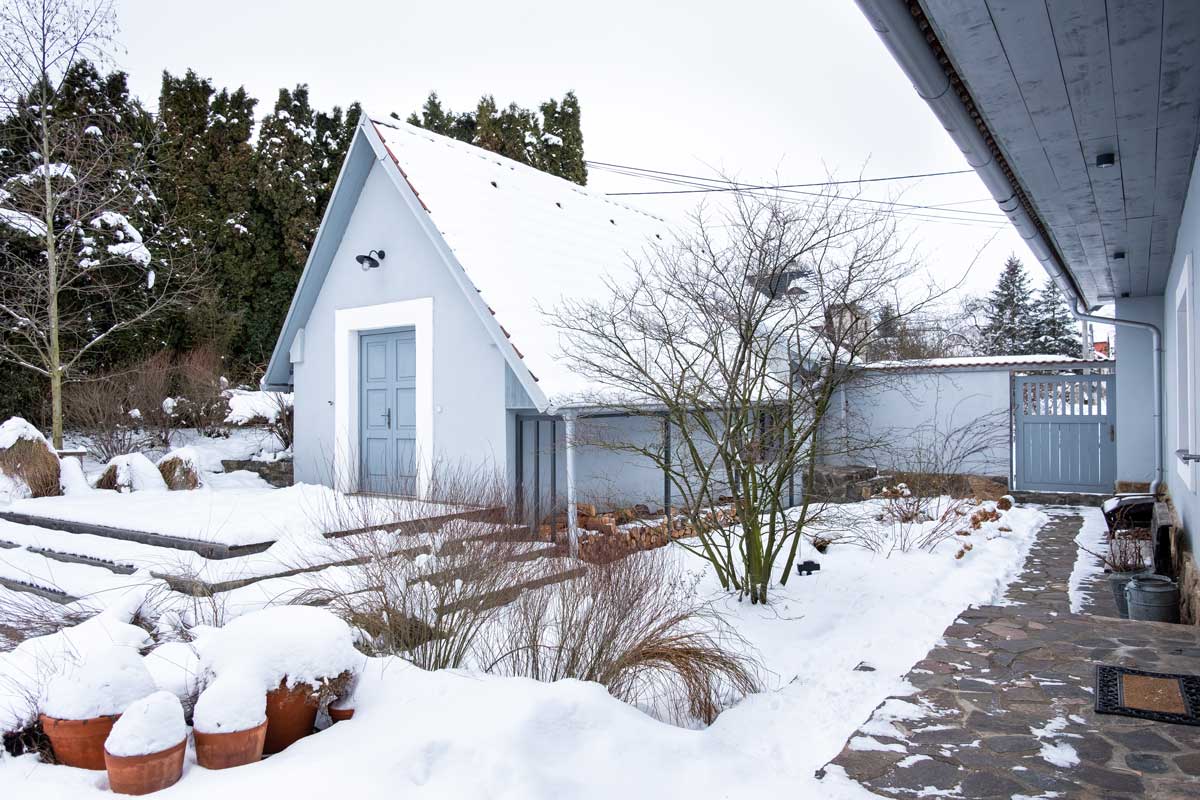 Jemná šedá omítka na fasádě budov i na zděném plotě zapadá do zimní scenérie.