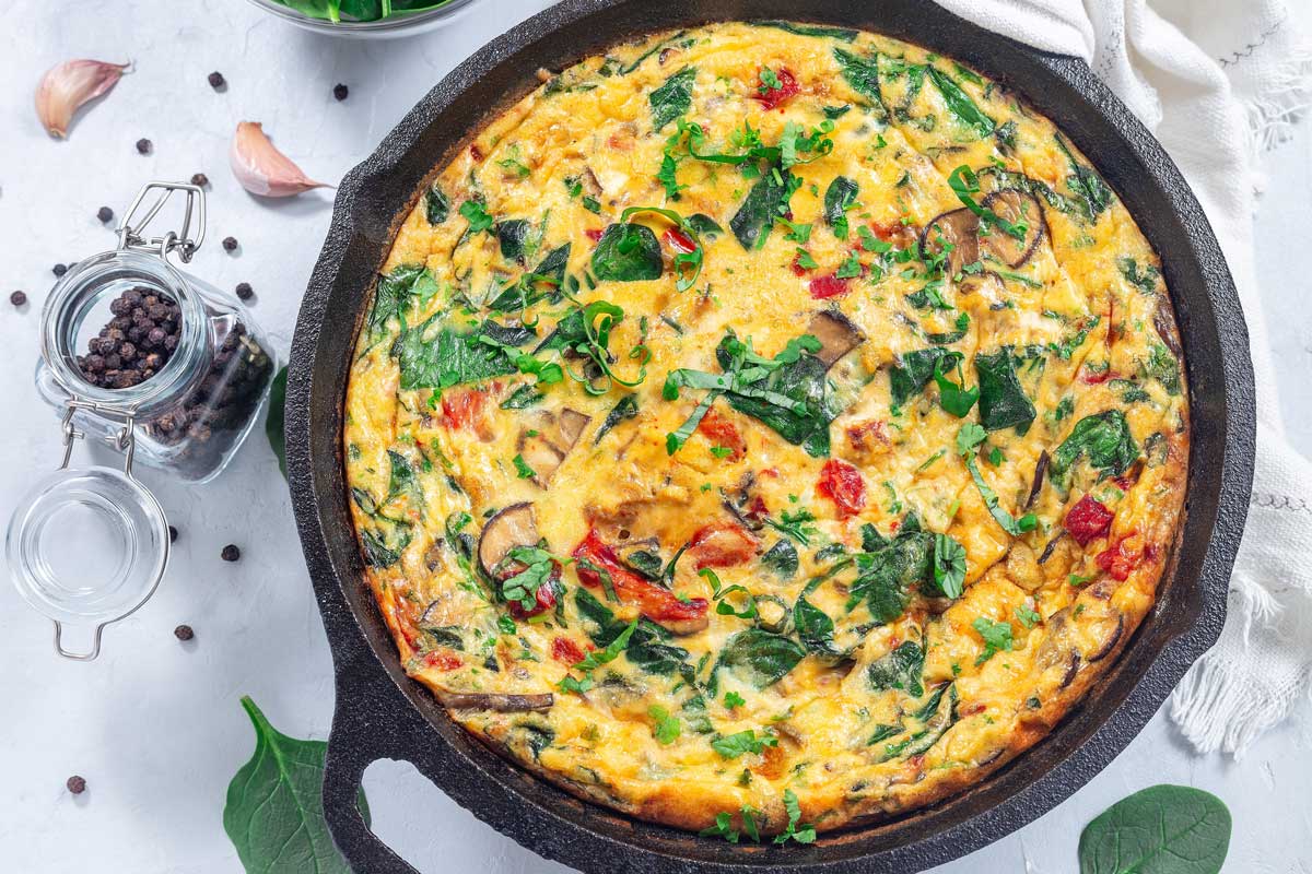 Zapečená frittata se špenátem, sýrem a zeleninou připravená na pánvi jako jednoduché low carb jídlo.