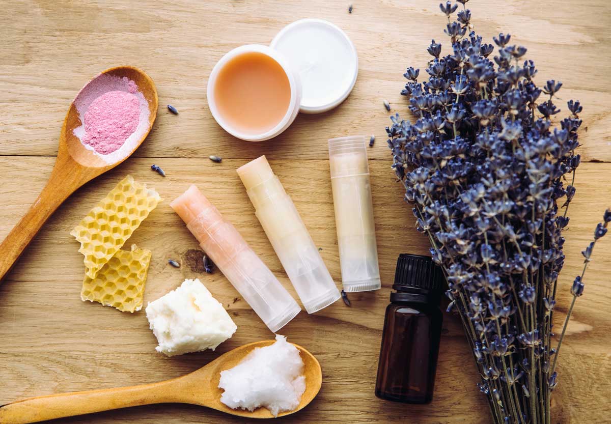 Ingredience na domácí balzám na rty včetně včelího vosku, bambuckého másla, levandule a esenciálních olejů