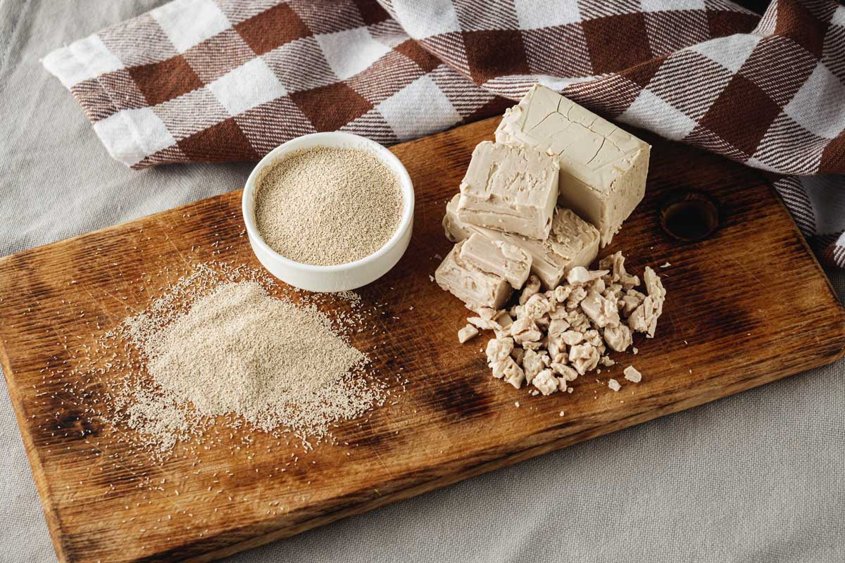 drozdi Čerstvé a sušené droždí na dřevěném prkénku, základní surovina pro kynuté těsto