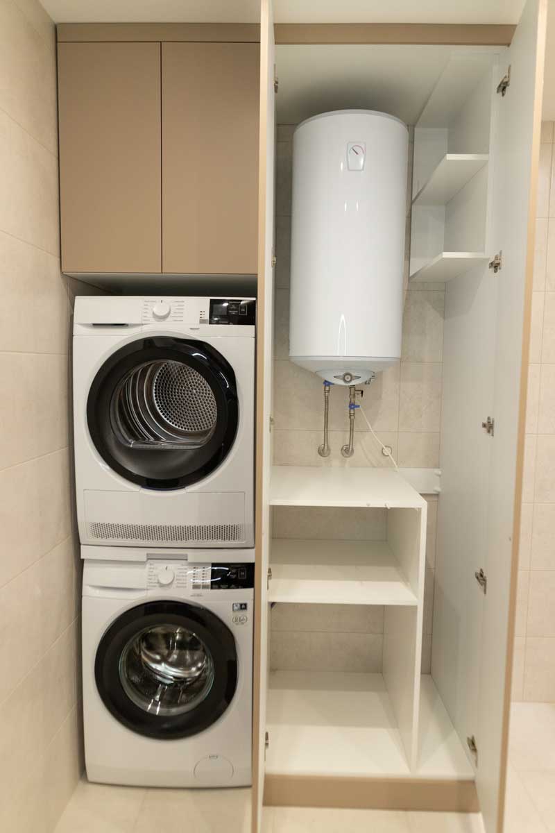 kotel ve skrini Bojler a pračka jsou ukryté ve vysoké skříni s policemi, které zároveň poskytují úložný prostor pro domácí potřeby.