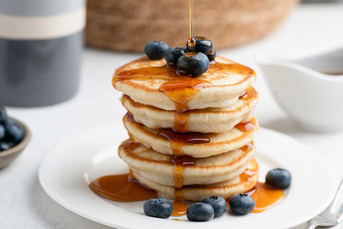 Low carb lívance z mandlové mouky podávané s borůvkami a sirupem jako sladká snídaně bez lepku.