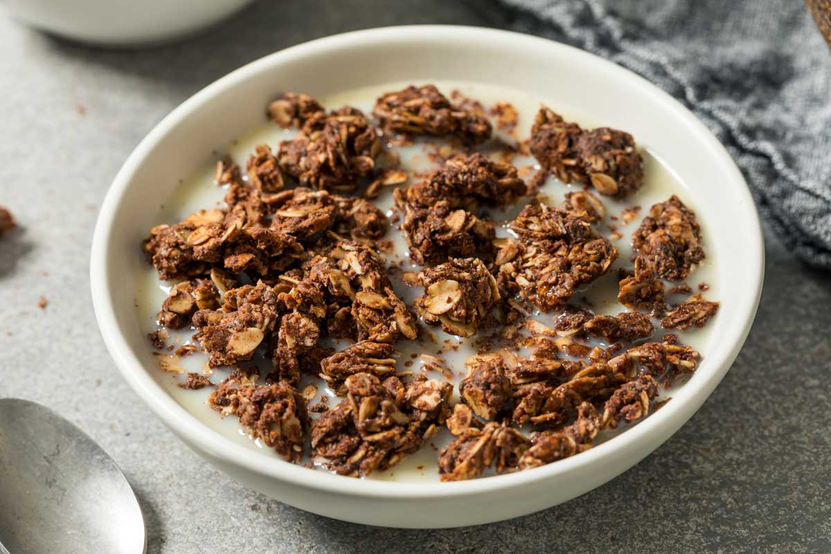 Křupavá granola s ovesnými vločkami a ořechy podávaná s mlékem jako snídaně