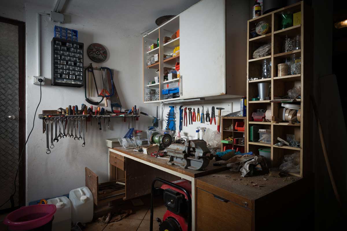 Pracovní kout v garáži s nářadím zavěšeným na stěně a pracovní deskou pro drobné opravy.