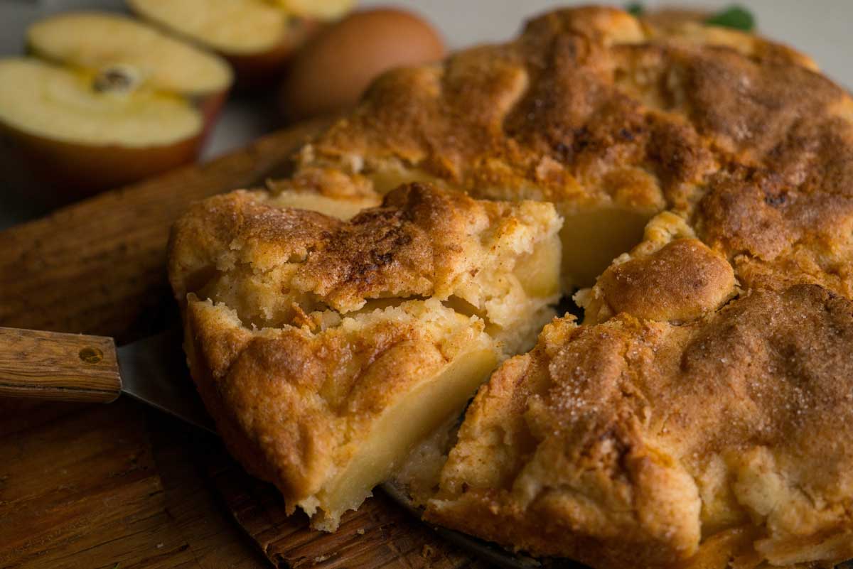 Švédský jablečný koláč nakrájený na porce s viditelnými kousky jablek a zlatavou křehkou vrstvou na povrchu.