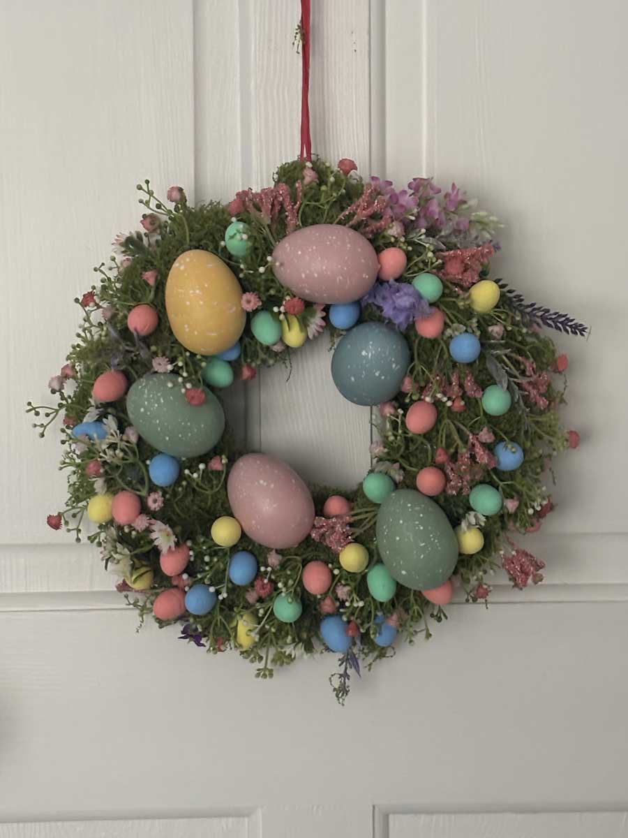 velikonocny venec Bohatý velikonoční věnec s barevnými vajíčky a květinami zavěšený na dveřích