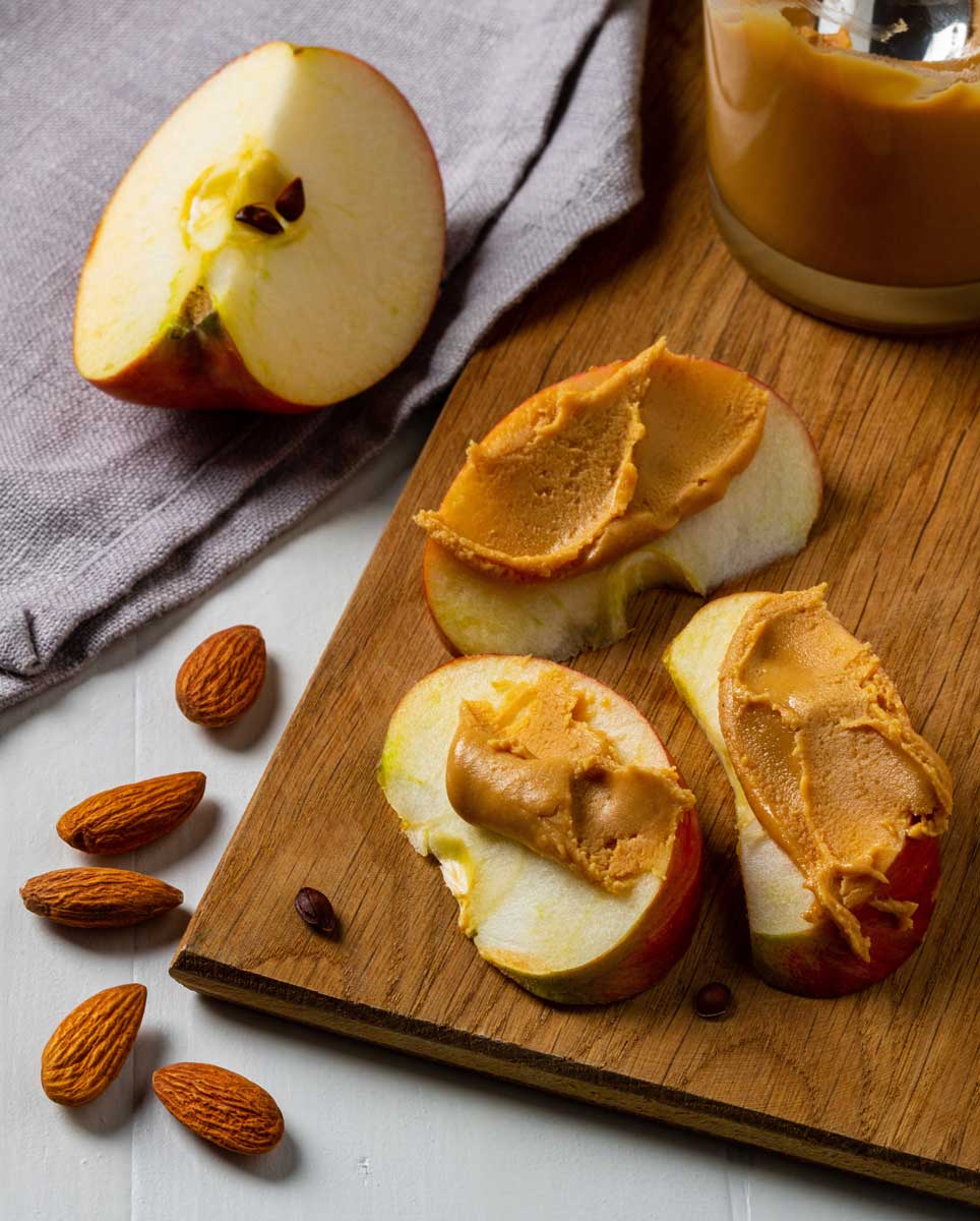 Plátky jablka s mandlovým máslem a skořicí jako jednoduchá zdravá svačina.