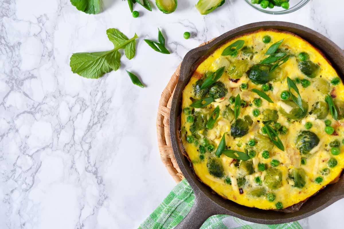 Jarní frittata se zeleninou a bylinkami připravená na pánvi jako lehké hlavní jídlo.