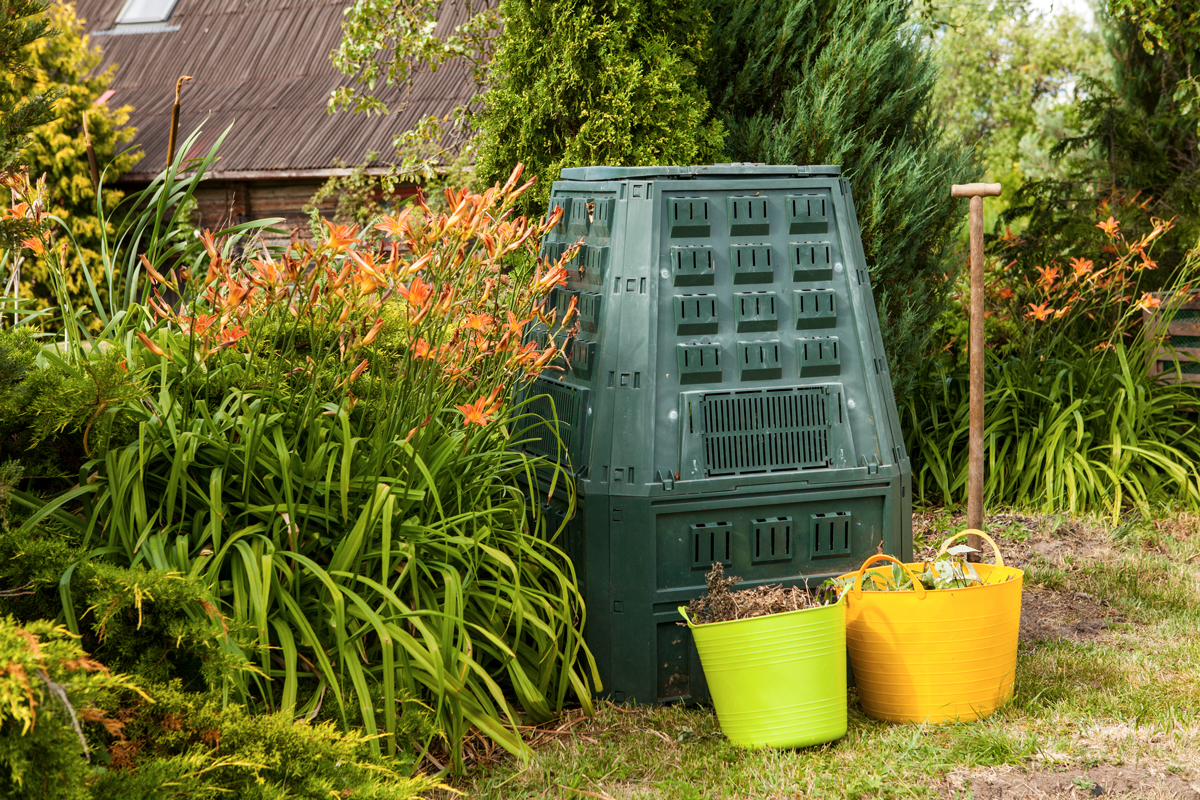 Zahradní kompostér ukrytý mezi rostlinami může při manipulaci uvolňovat plísně a spory do ovzduší.