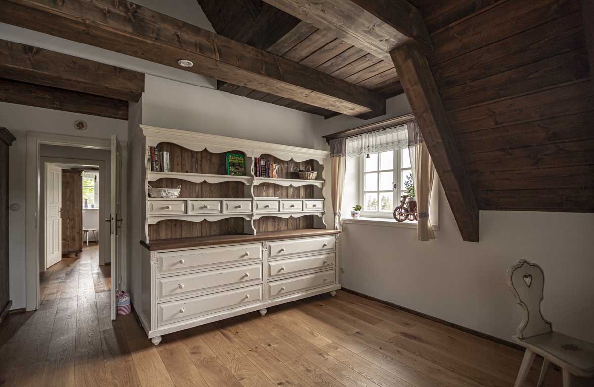 Starožitný kredenc v interiéru roubenky doplněný dekoracemi s venkovskými motivy.