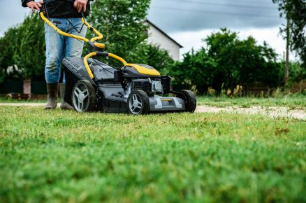 Sekání trávníku na jaře v dubnu v období proměnlivého počasí a růstu trávy.