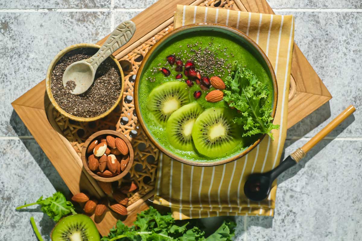 Zelená smoothie bowl s kiwi, mandlemi a chia semínky jako výživná snídaně plná vitamínů.