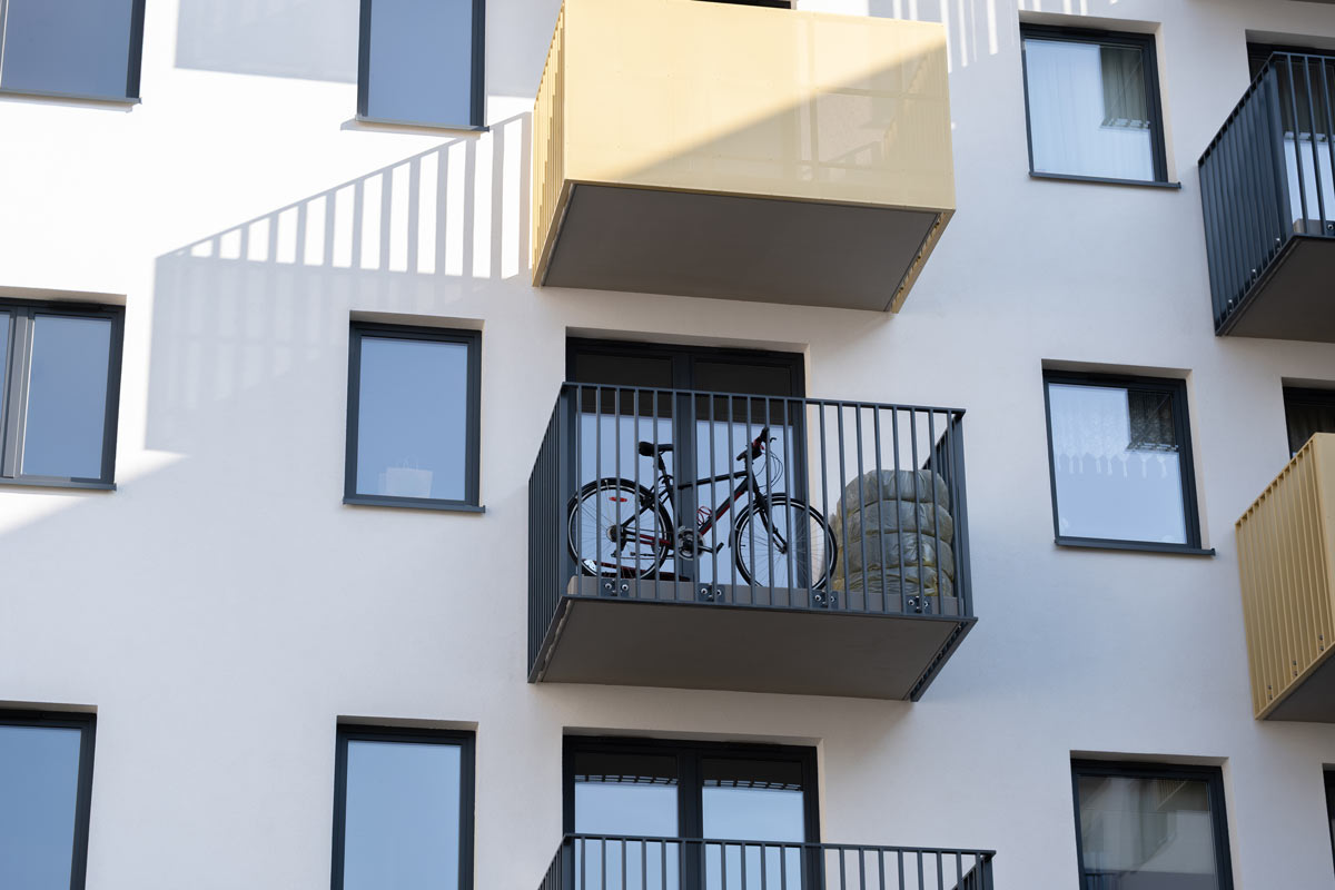 Balkon bytového domu využitý k odkládání kola a velkých předmětů místo posezení.