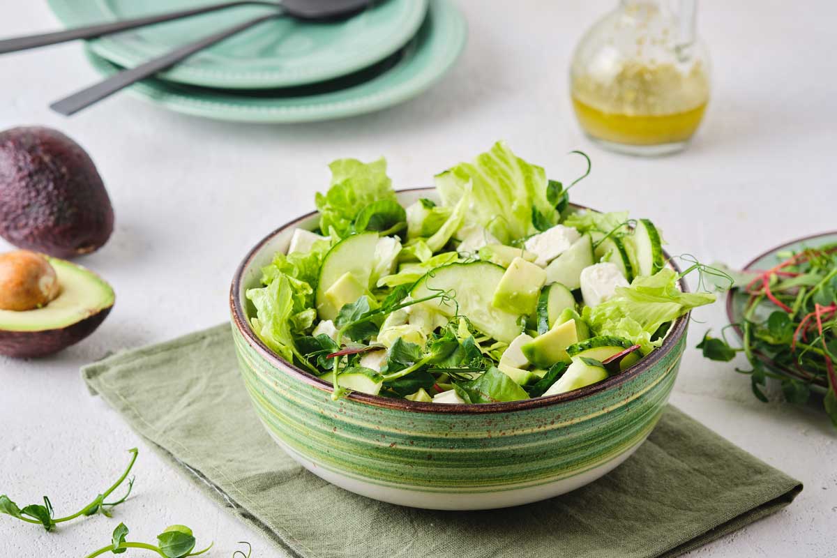Zeleninový salát s avokádem, okurkou a listovou zeleninou podávaný ve stylové misce.