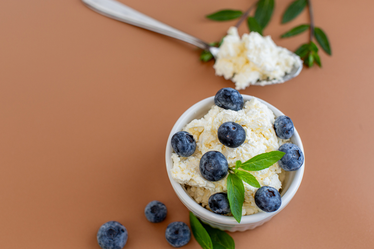 Proteinová zmrzlina z cottage sýra je ozdobená borůvkami a čerstvou bazalkou.