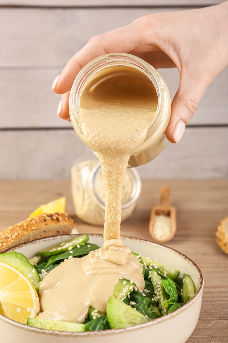 tahini dresink Krémový tahini dresink nalévaný na zeleninový salát jako základ chutného a výživného salátu do sklenice.