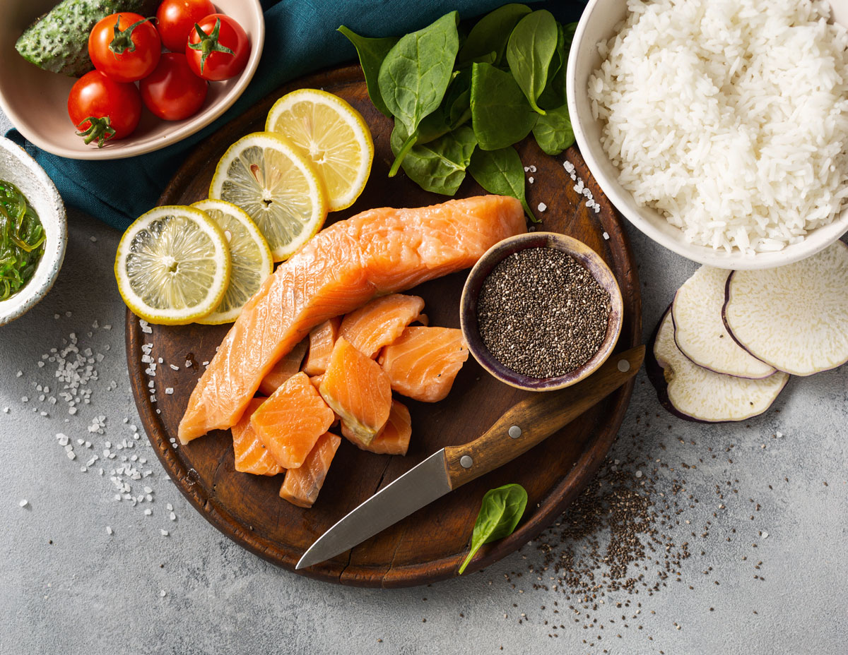 ingredience poke bowl Suroviny pro přípravu lososové poke bowl zahrnující lososa, rýži, citron, chia semínka a čerstvou zeleninu.