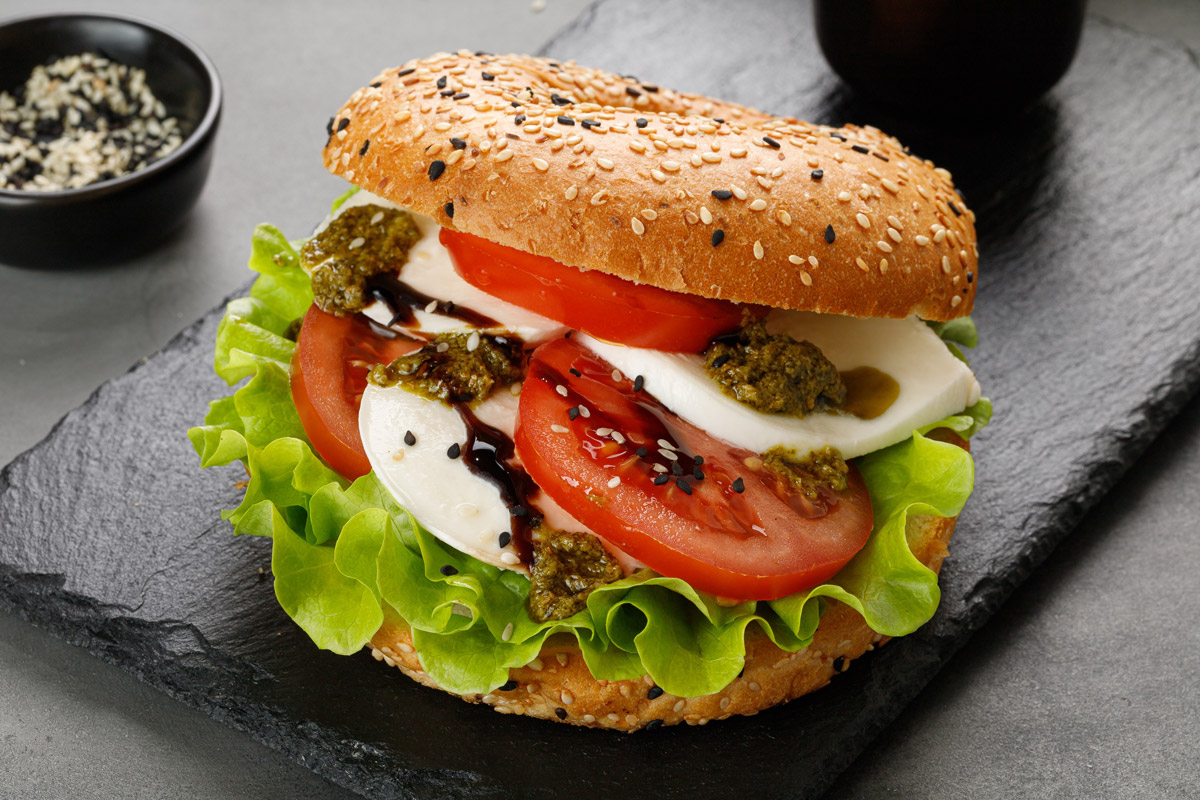 bagel s rajcatami Bagel s rajčaty, mozzarellou, pestem a listovým salátem je lehkou letní svačinou na výlet.