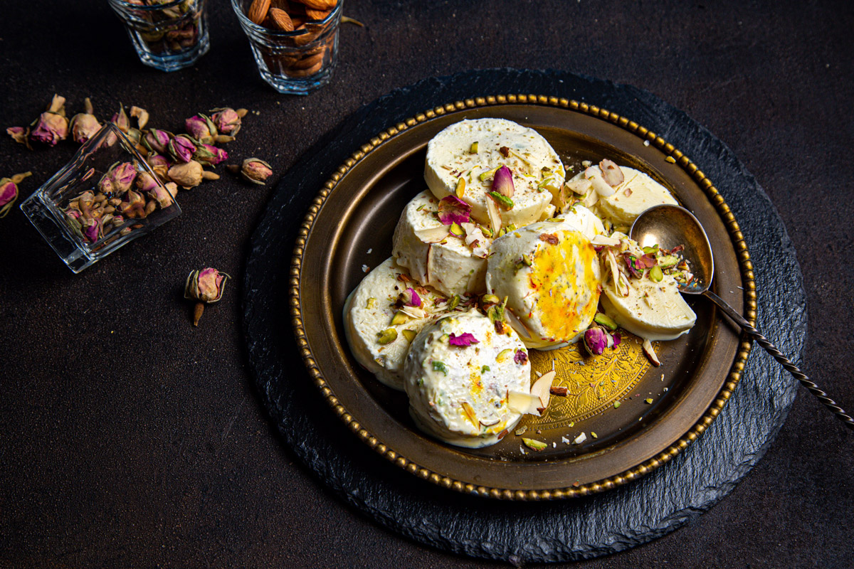 kulfi servirovani Tradiční indické kulfi nakrájené na plátky je ozdobené pistáciemi, mandlemi, šafránem a sušenými růžemi. Podává se jako mražený dezert místo klasické kopečkové zmrzliny.