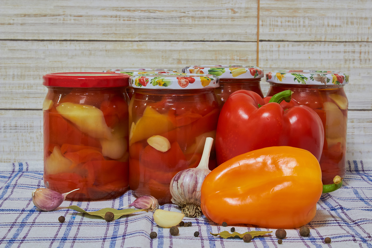 nakladana paprika 1 Sklenice s nakládanými červenými a žlutými paprikami doplněné čerstvými paprikami, česnekem, bobkovým listem a celým kořením.